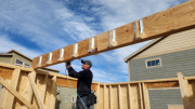 Bob nailing joist hangers above studio